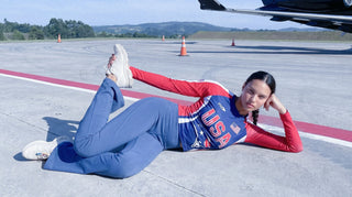 Person in athletic wear lying on a runway with an airplane in the background